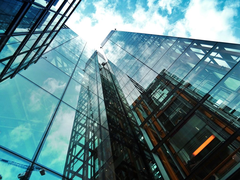 A striking view of a modern glass skyscraper reflecting the sky and clouds.