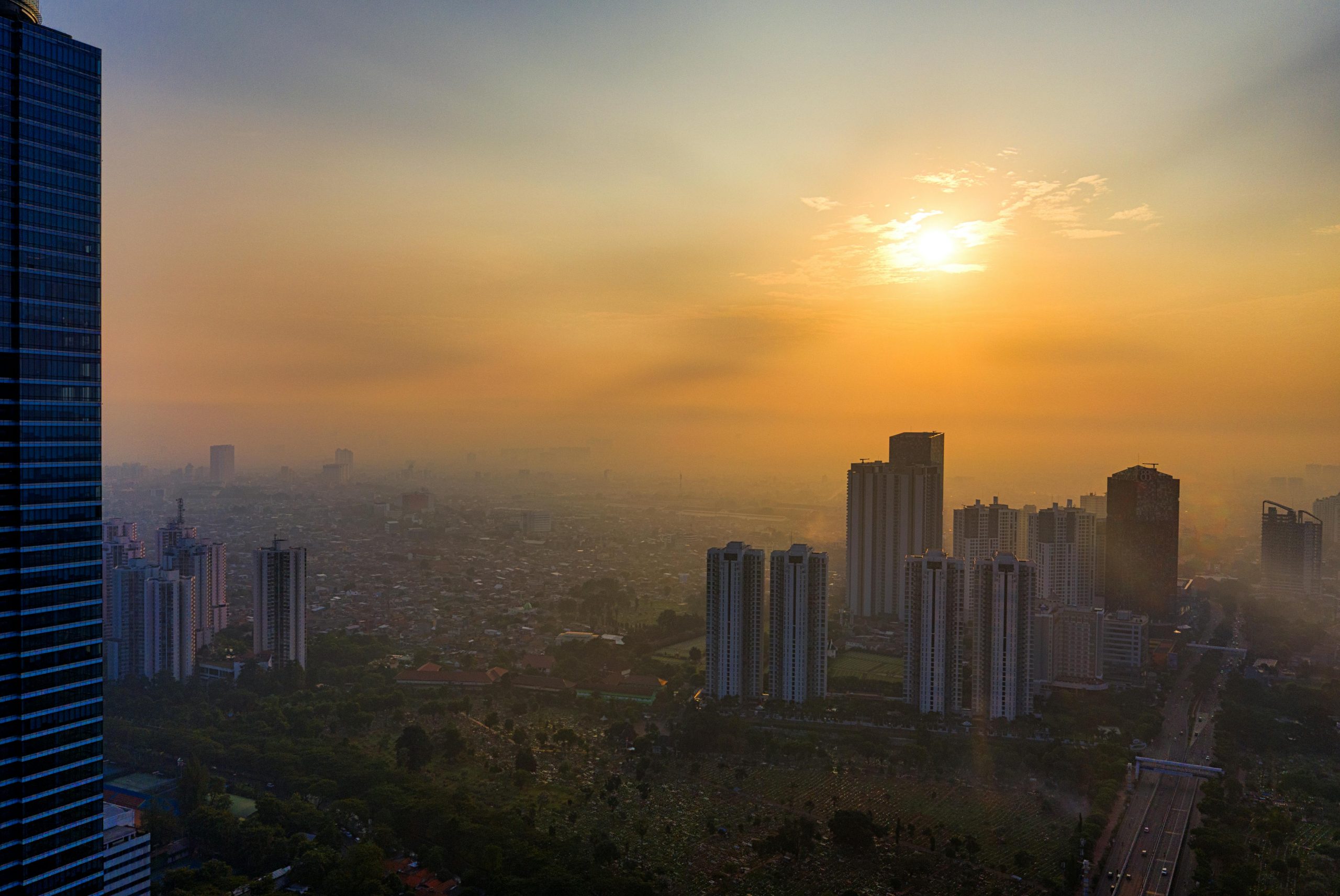 Aerial view of South Jakarta with skyscrapers silhouetted by a stunning sunset.